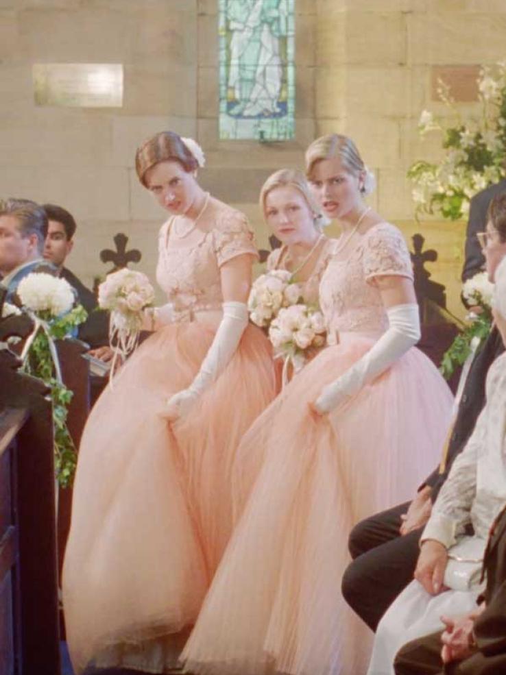 Three bridesmaids in peach-coloured gowns at a wedding in a scene from the film Muriel's Wedding