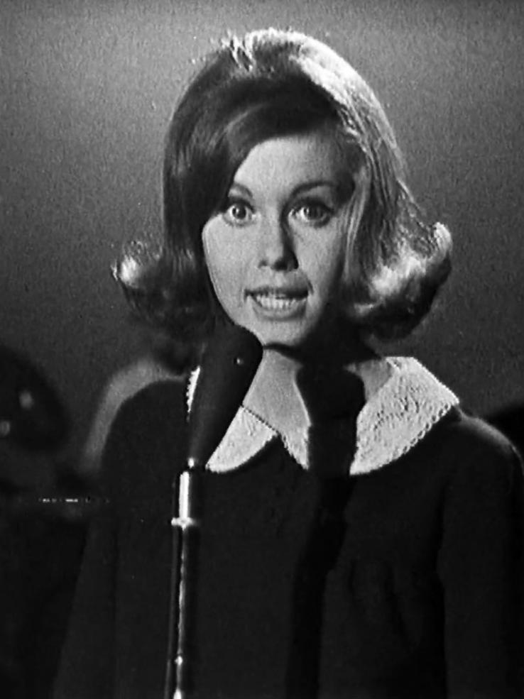 Singer Olivia Newton-John singing into a microphone, circa 1965