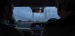 View out of the front windscreen of a car from the back seat of the driver and passenger, they appear to be crossing over a bridge. 
