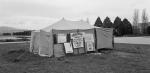 A large tent set up in the middle of a field. There are signs on the front of the tent - one of them reads Aboriginal Tent Embassy.