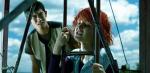 A confused-looking young man looks at a young woman who has her eyes closed and is holding on tightly to a metal ladder.