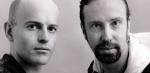 Close up of two men standing side by side and looking intently into the camera.