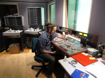 Tecnhician in a studio seated at a desk conducting analogue processing.