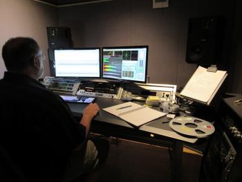 Technician seated behind a computer desk in the Mastering studio.