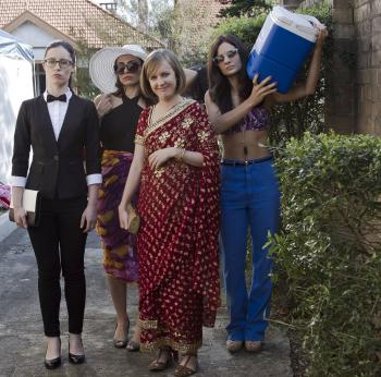 Four women walk towards the camera. One carries an esky.