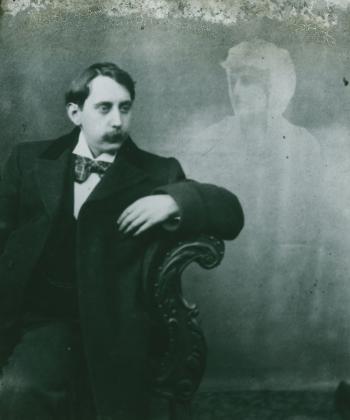 Black and white glass slide showing a man sitting sideways on a chair, elbow resting over side of chair, with a spirit hovering at his left.
