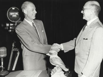 Two middle-aged men in suits shaking hands.