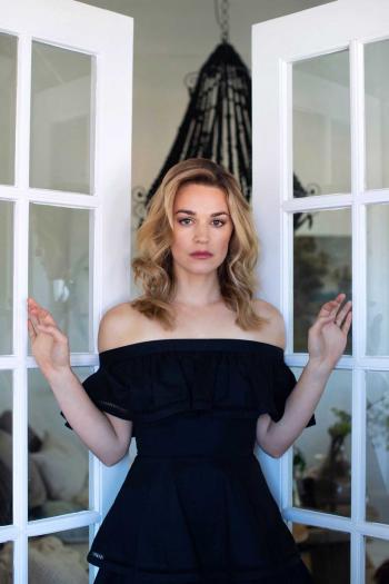 Actress Laura Gordon in a black dress standing between two open French doors