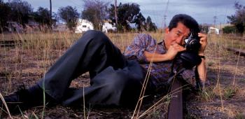 A man lying on his side on the ground taking a photograph