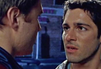 Two men talking close together on the street at night