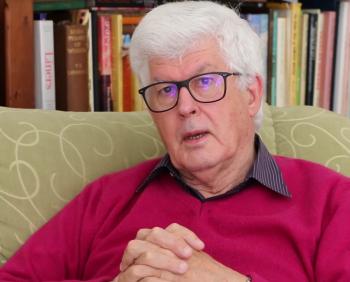 Anthony Buckley seated at home with his hands clasped being interviewed.