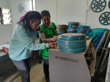 Two archivists inspecting a pile of film cans in the National Film Institute of Papua New Guinea