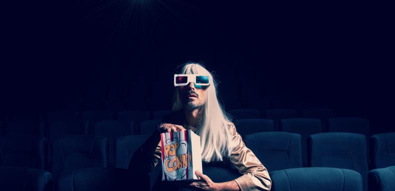 Person sitting in empty cinema wearing 3D glasses and eating popcorn