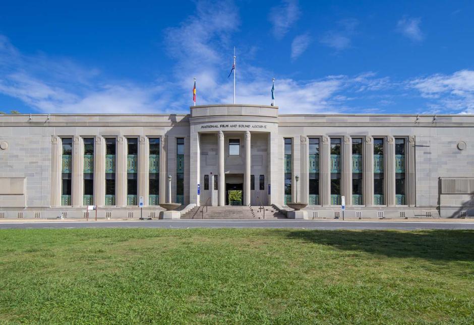A view of the National Film and Sound Archive Art Deco building in Canberra as seen across a grass lawn