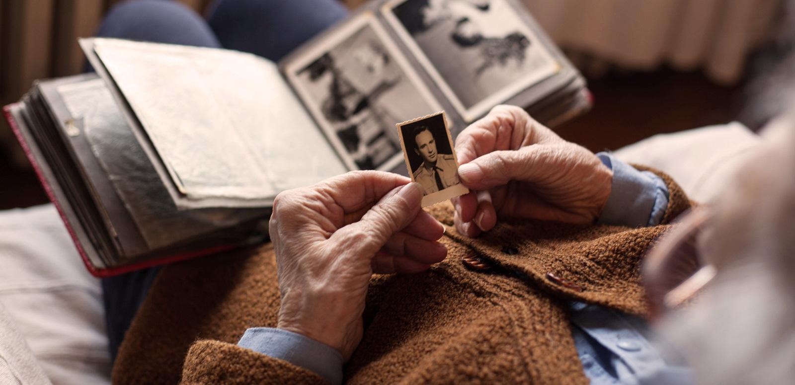 An elderly person looking at an old photo album