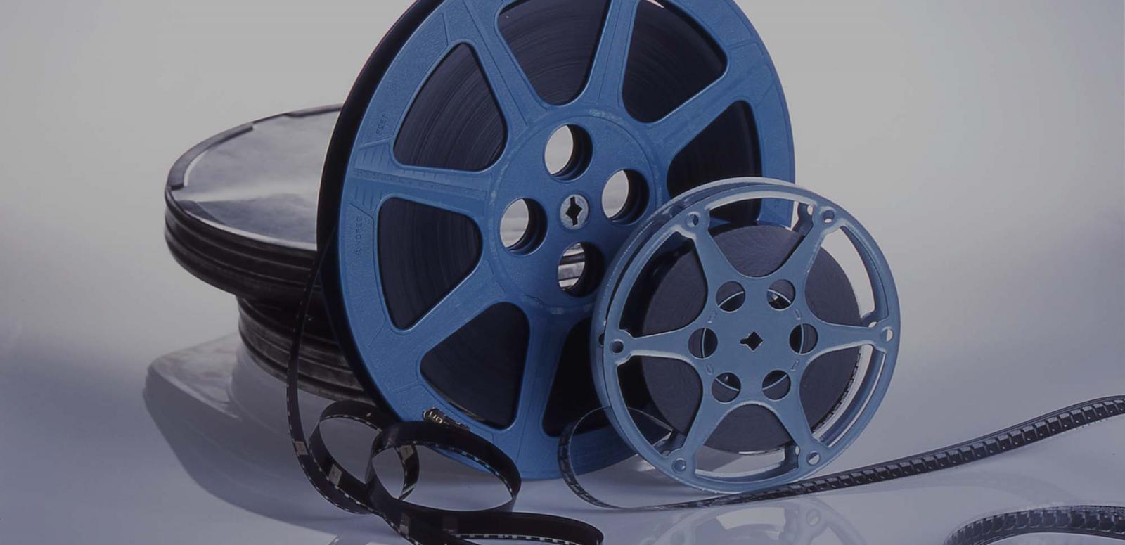 Two film canisters sit on a table service with the film partially unwound.