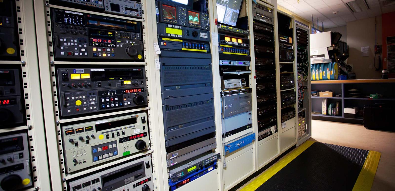 A rack metal rack houses video tape players and monitors
