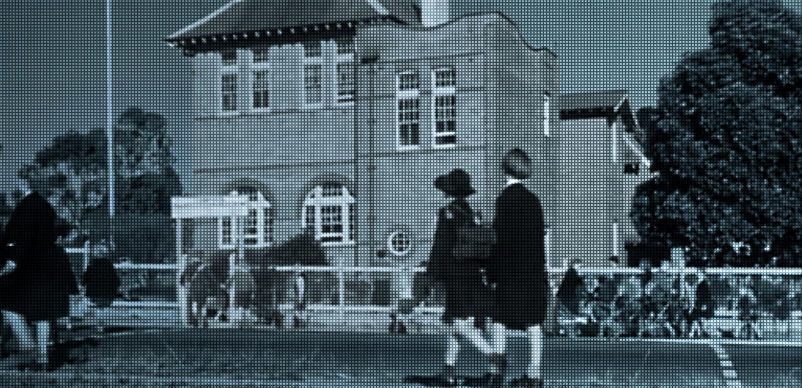 School kids walking towards a big sandstone school building. 