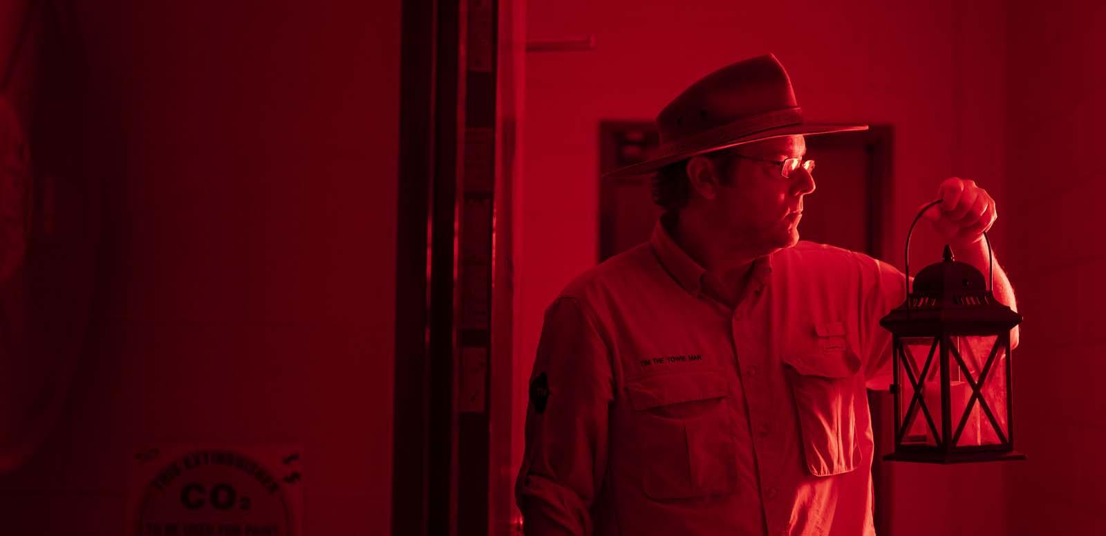 Tim the Yowie Man holding a lantern backstage during the NFSA Ghost Tour