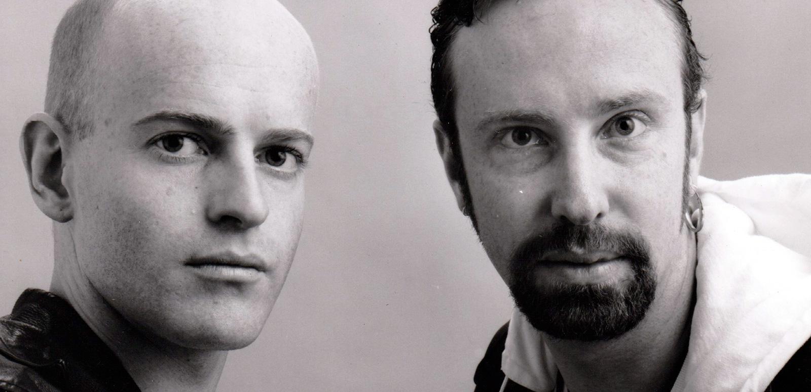Close up of two men standing side by side and looking intently into the camera.