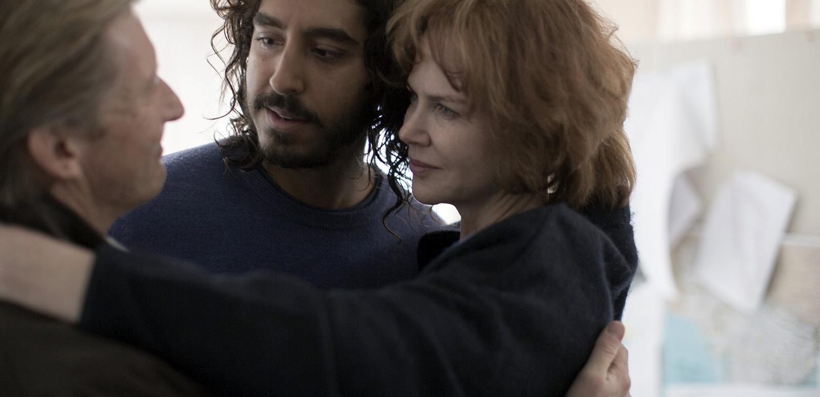 Family shot of a middle-aged man and woman embracing a young man