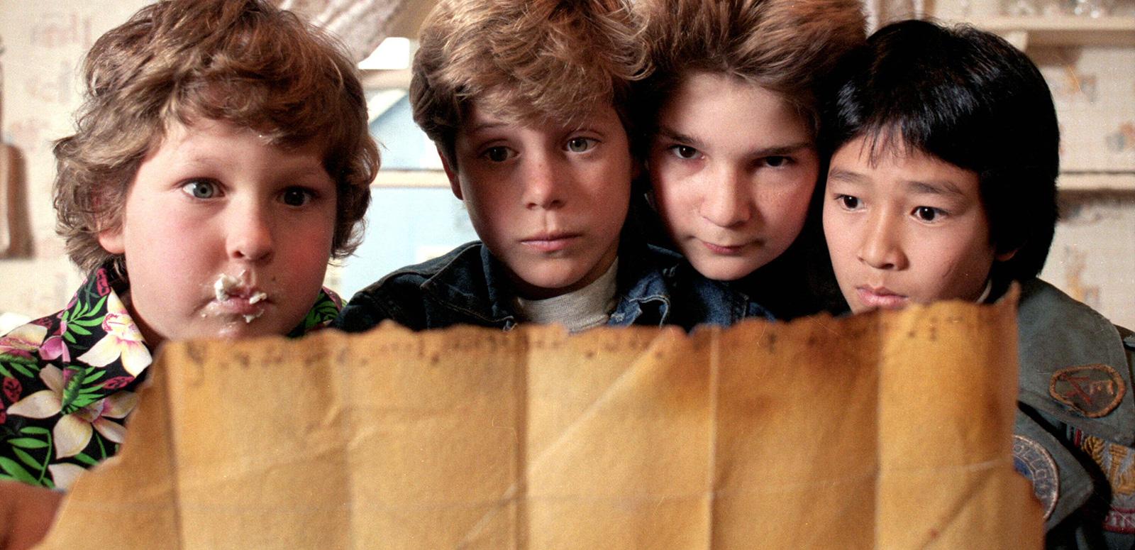 Head and shoulders shot of four young boys looking at an old treasure map.