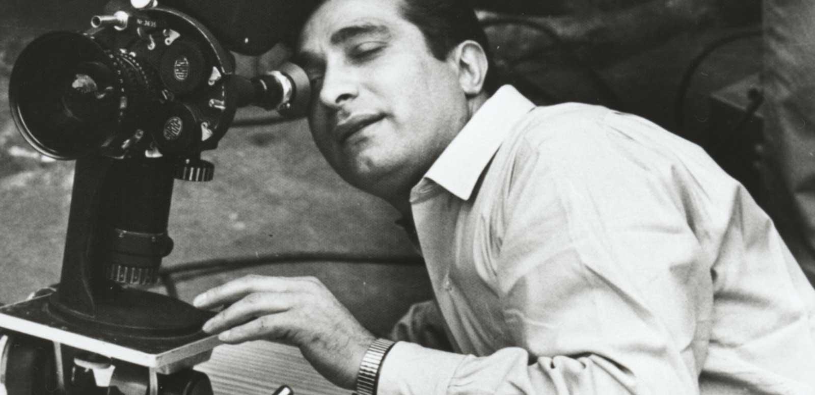 A man leaning over and looking into a movie camera