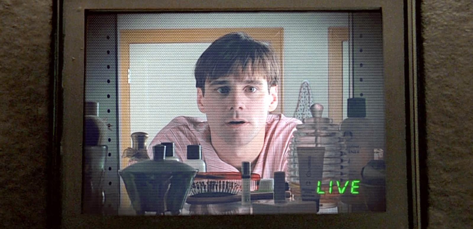 A man who appears to be in a kitchen staring blankly through a glass panel. The word 'LIVE' is written on the bottom right of the screen.