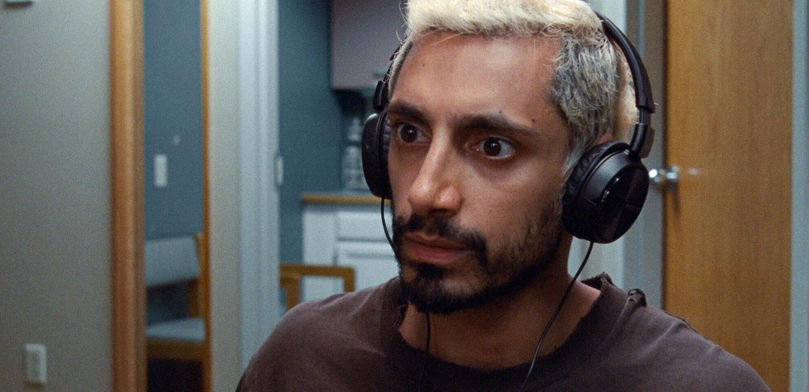 Close up of actor Riz Ahmed in a scene from Sound of Metal, wearing headphones
