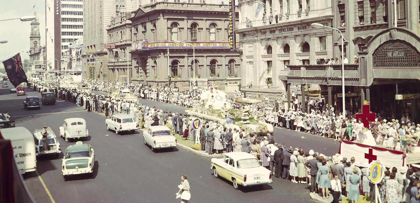 A main street of Adelaide lined with people and cars during a festival. 