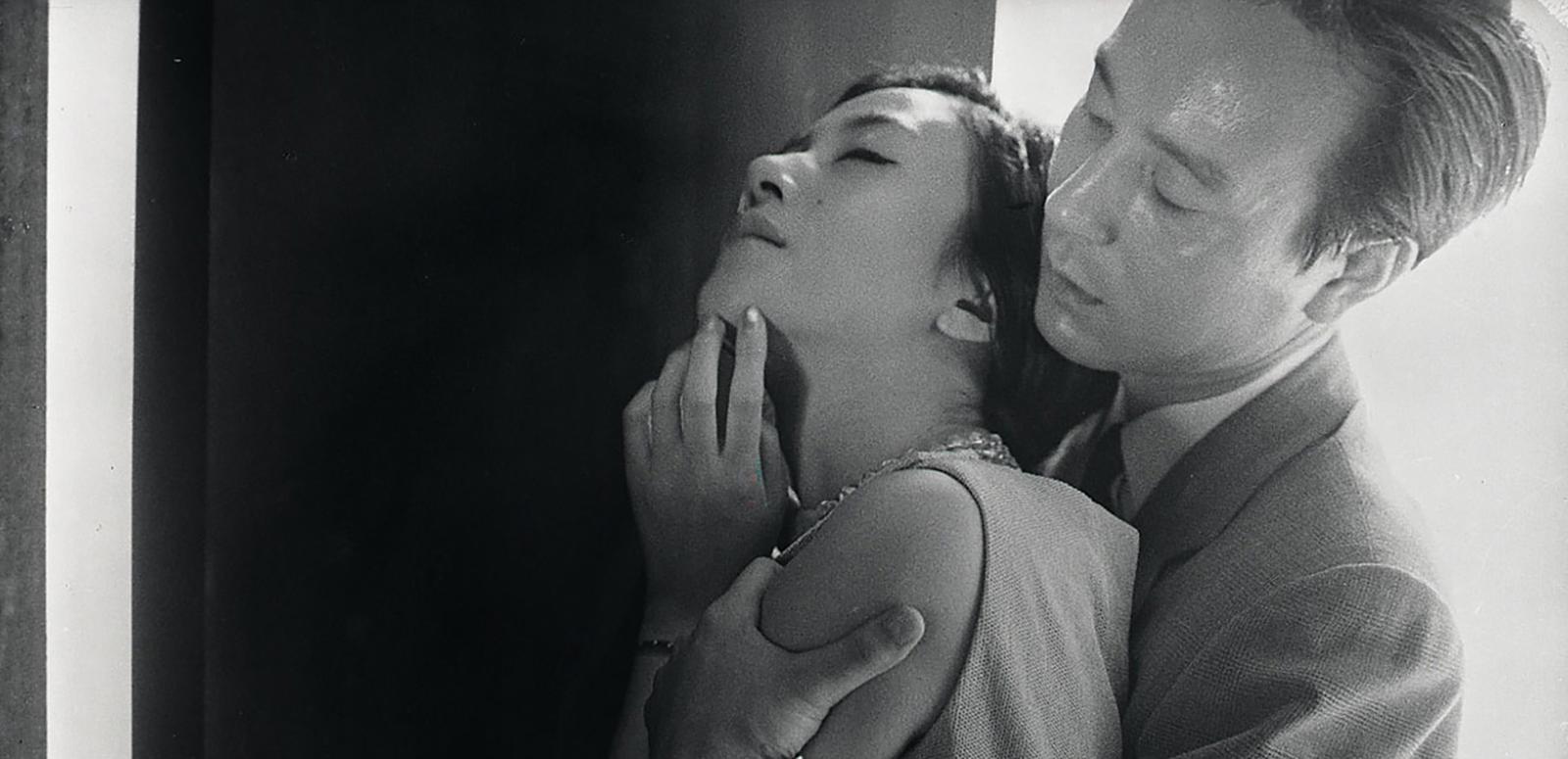 A woman standing with her back to a man who has his arms around her and is holding her tightly.