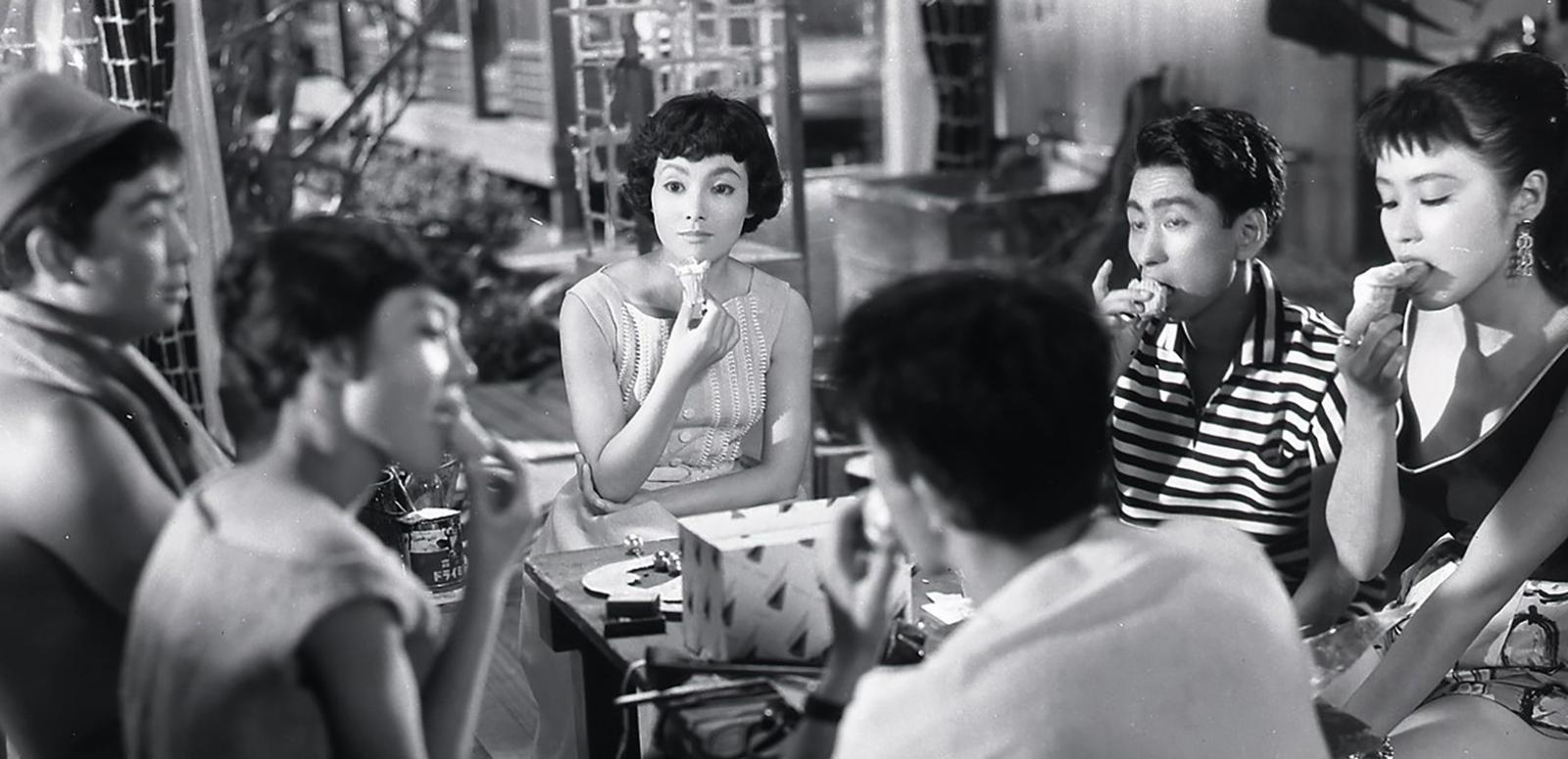 A group of Japanese people sitting around a table eating ice cream cones