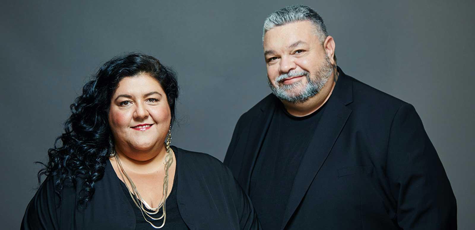 Head and shoulders image of Indigenous filmmakers Gillian Moody and Adrian Russell, both dressed in black and smiling at the camera.