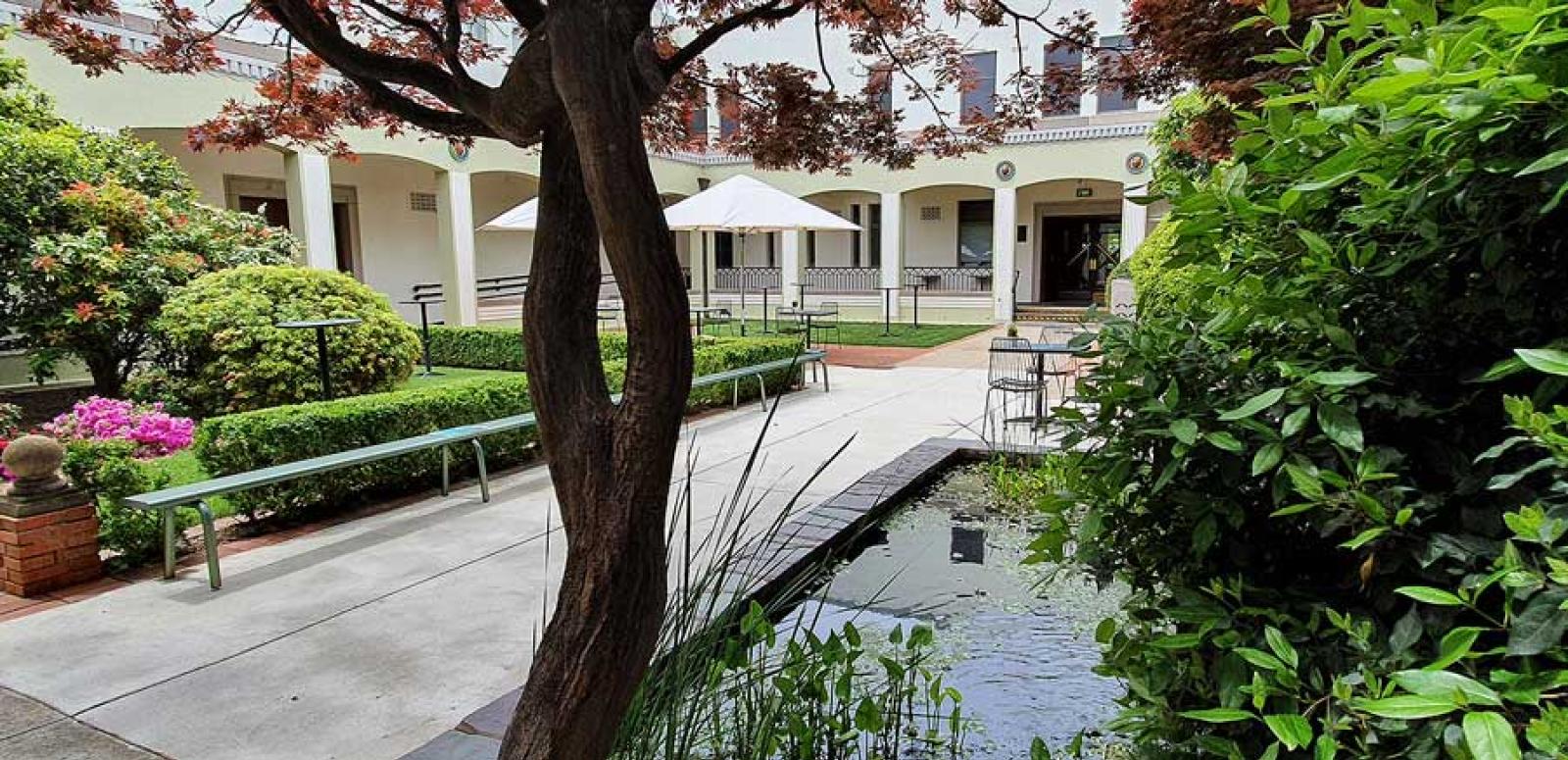 The courtyard at the NFSA with the pond in the front and tables and umbrellas in the background