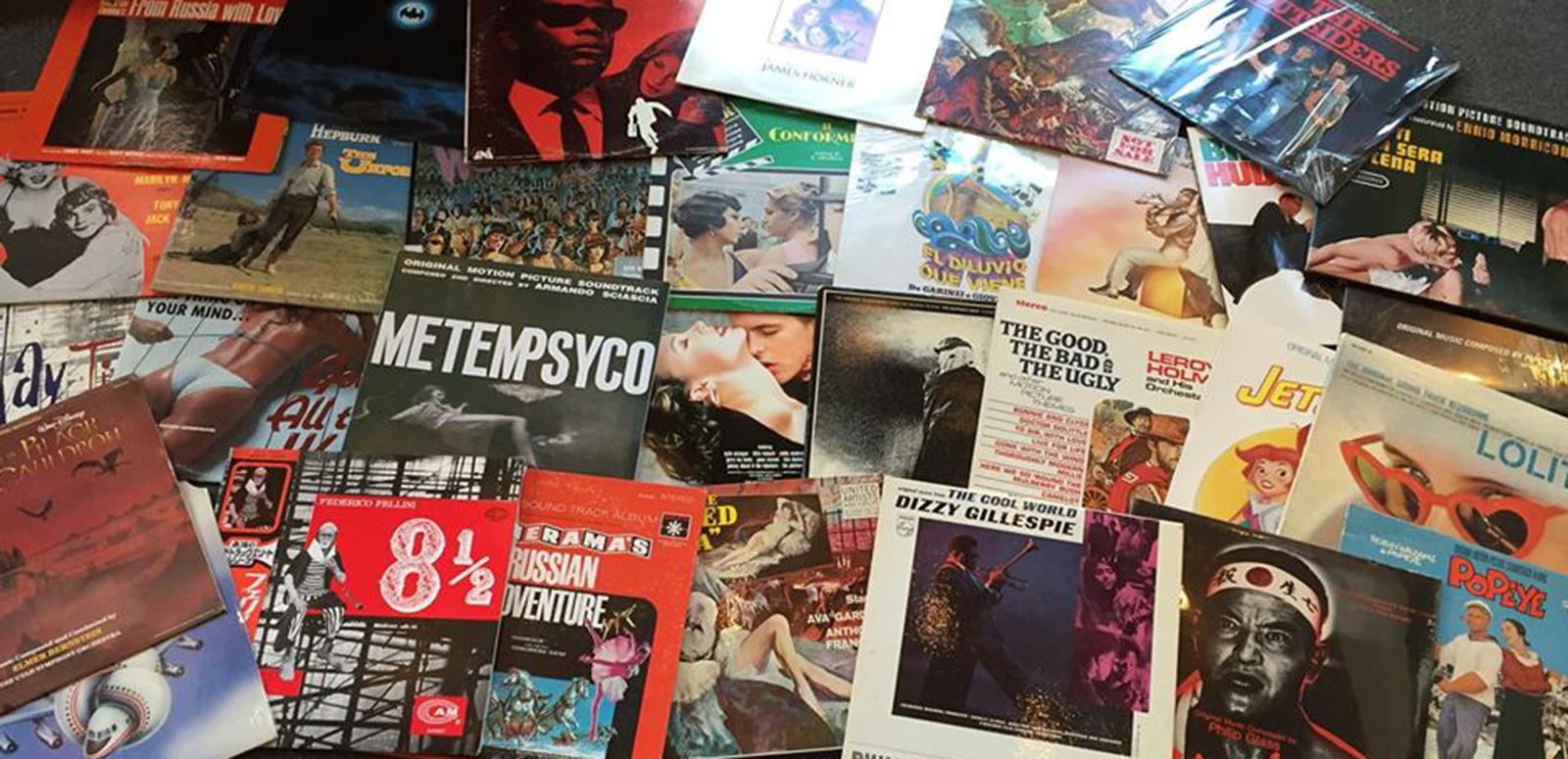 A lot of vinyl record covers spread out on a table all overlapping each other.