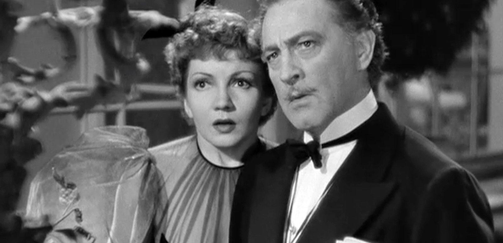 Head and shoulders shot of actors Claudette Colbert and John Barrymore in formal attire, they are both looking straight ahead and seem to be surprised at something. From a 1929 film Midnight.