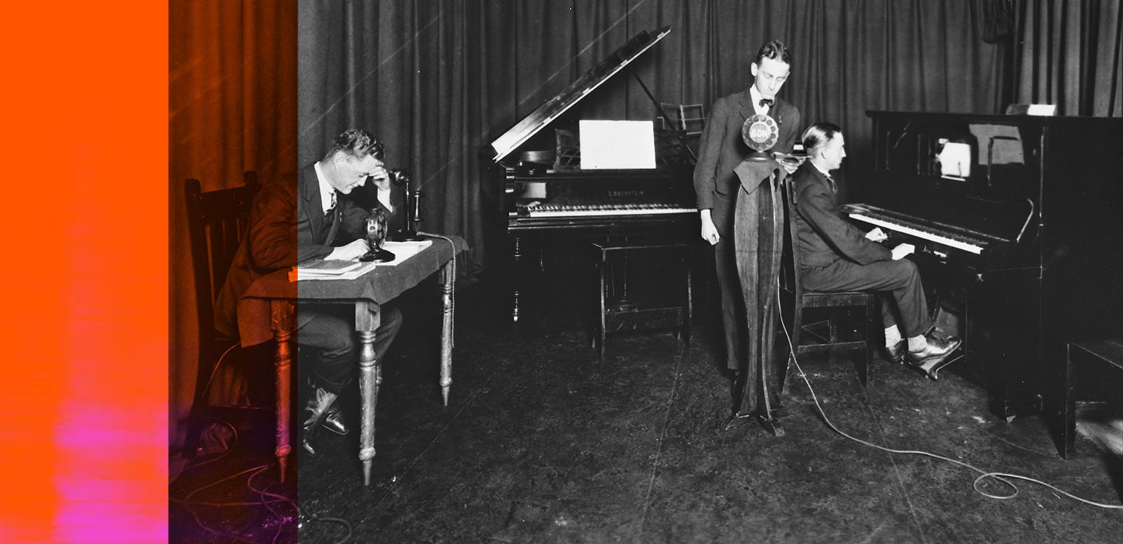 Recording a radio program from a home recording studio in 1927. One man sits at a desk, another at a piano while a third stands behind a microphone.