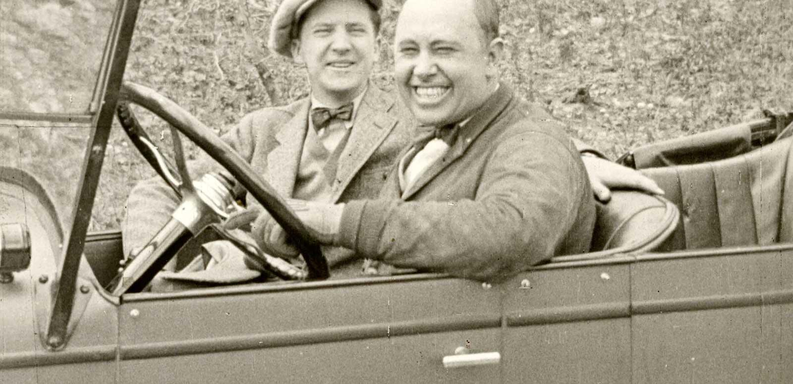 Two men sitting in a motor car and smiling at the camera, c1924.