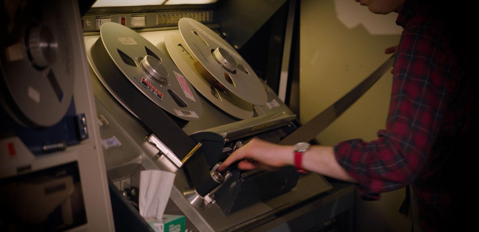 A person operating a reel-to-reel film scanner at the National Film and Sound Archive