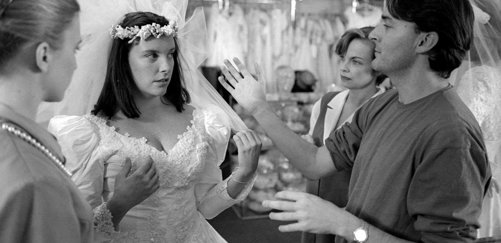 Toni Collette in a wedding dress standing with director PJ Hogan in a bridal store shooting a scene from Muriel's Wedding.