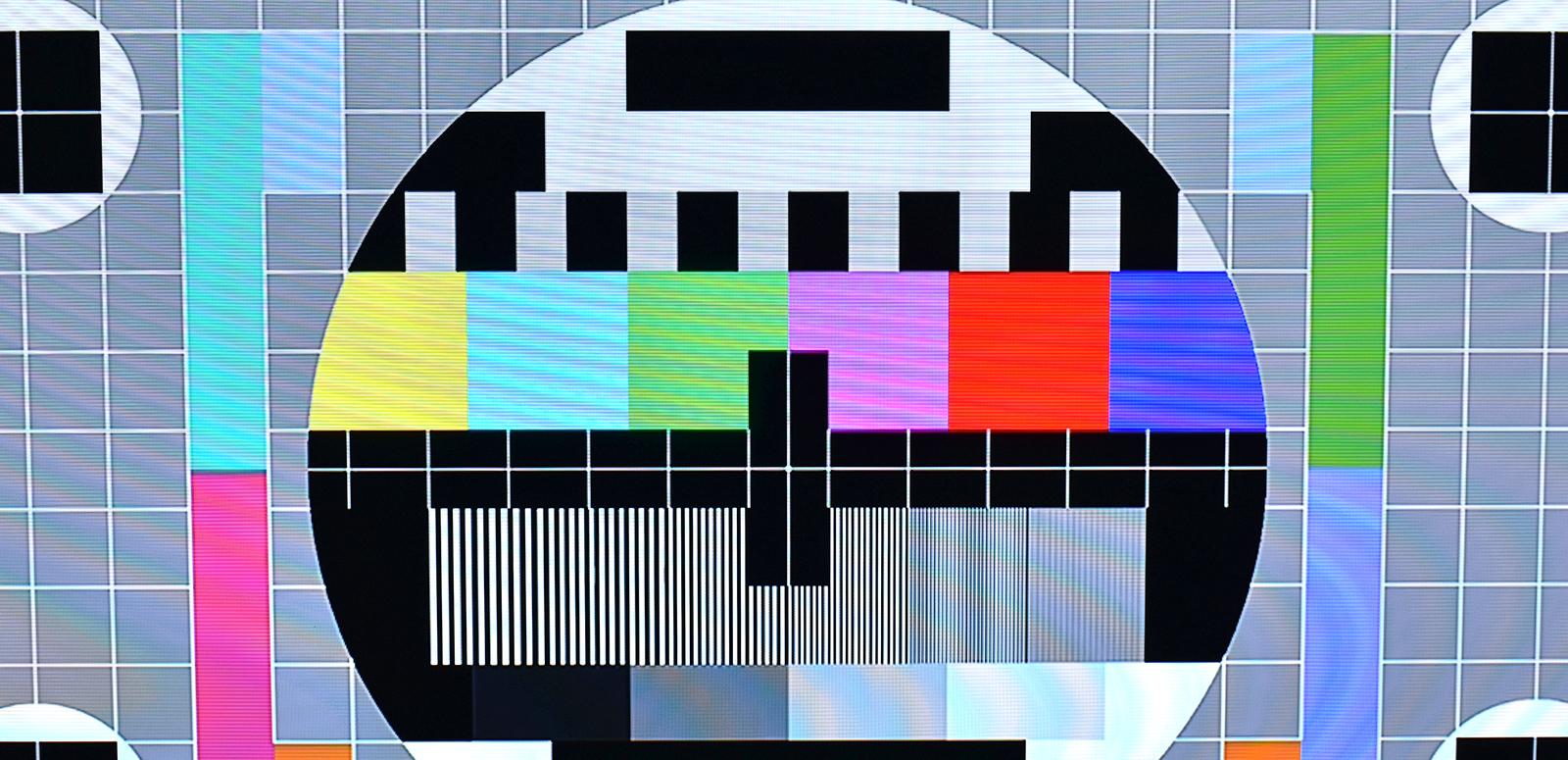 A TV test pattern with a circle made up of black, grey and coloured squares and rectangles in the centre of a grid