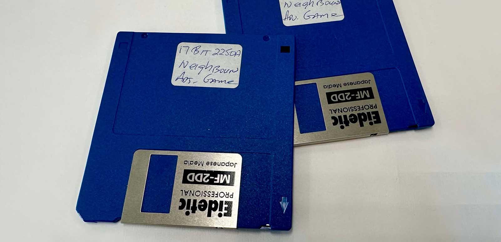 Two floppy disks with a handwritten label on them identifying them as a Neighbours video game.