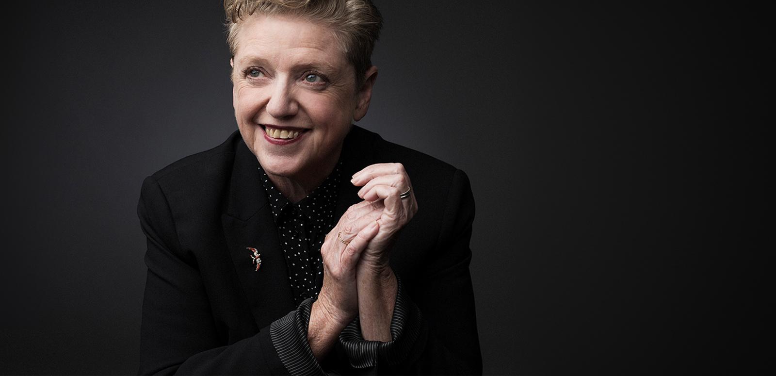 Robyn Archer smiling with her hands clasped in front of her