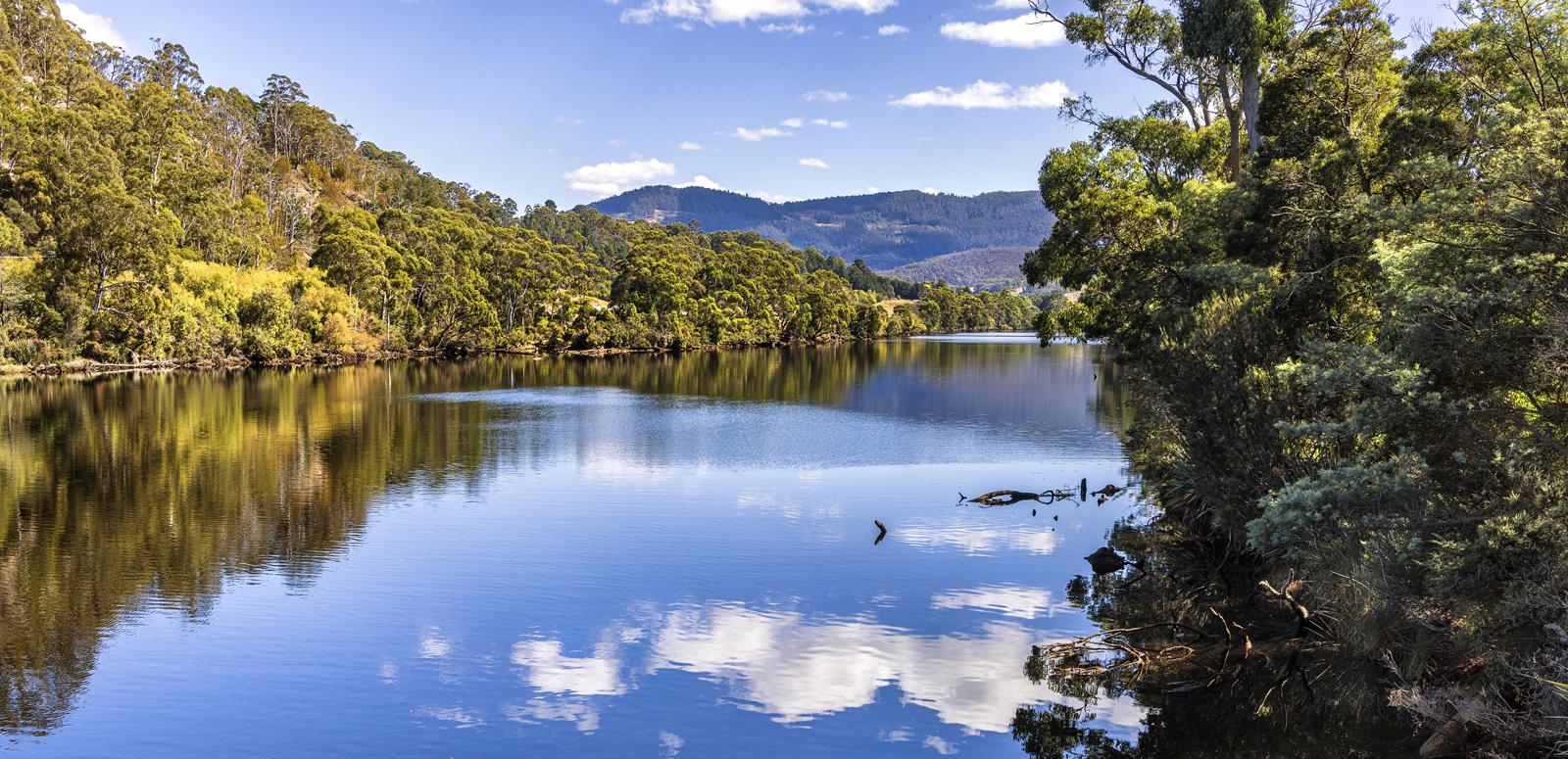 Clouds reflected on the Huon River on a sunny day in Tasmania