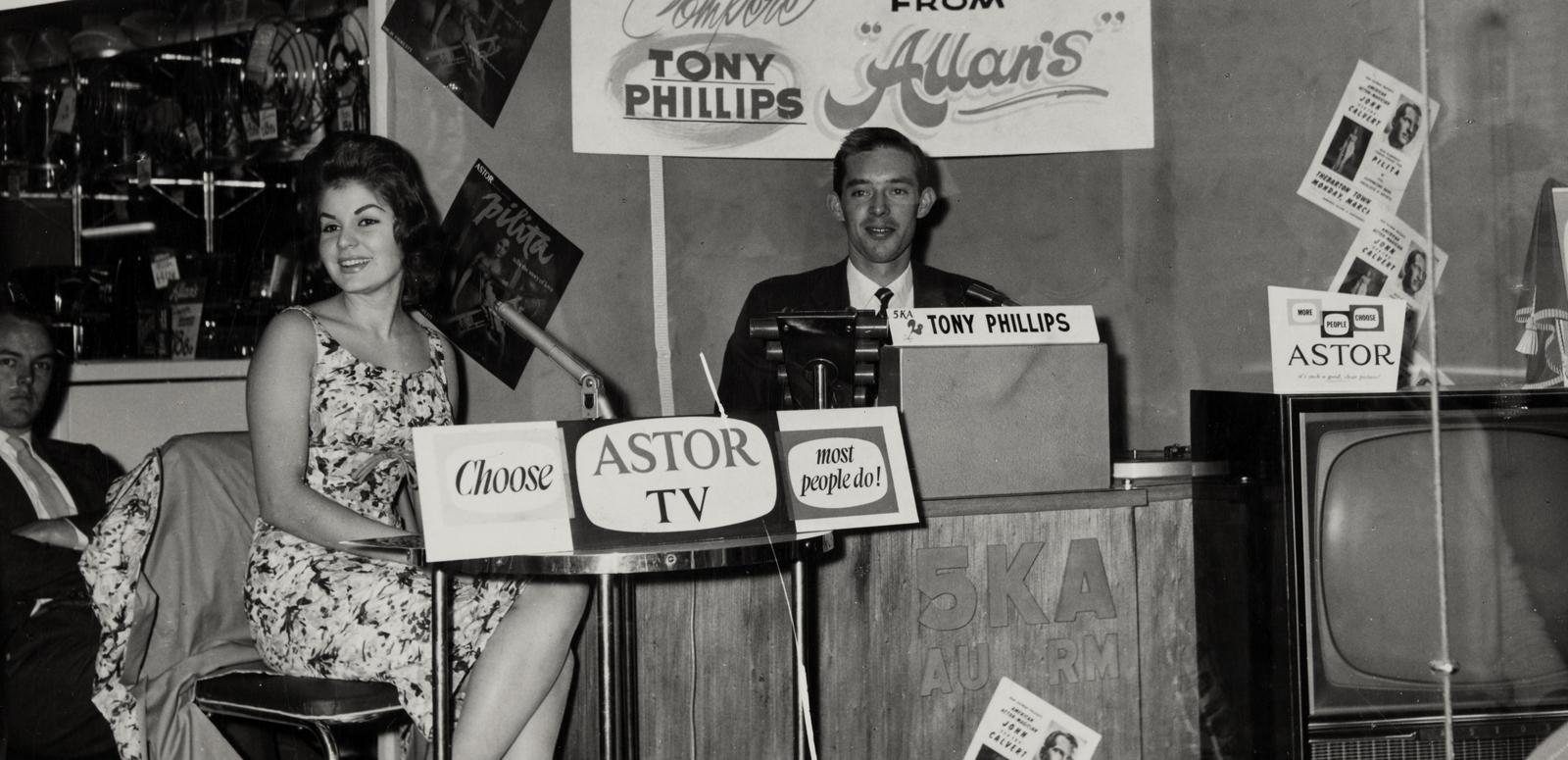 Pilita Corrales seated behind a desk at an outdoor broadcast with radio station 5KA DJ Tony Phillips. NExt to the desk is an Astor TV set
