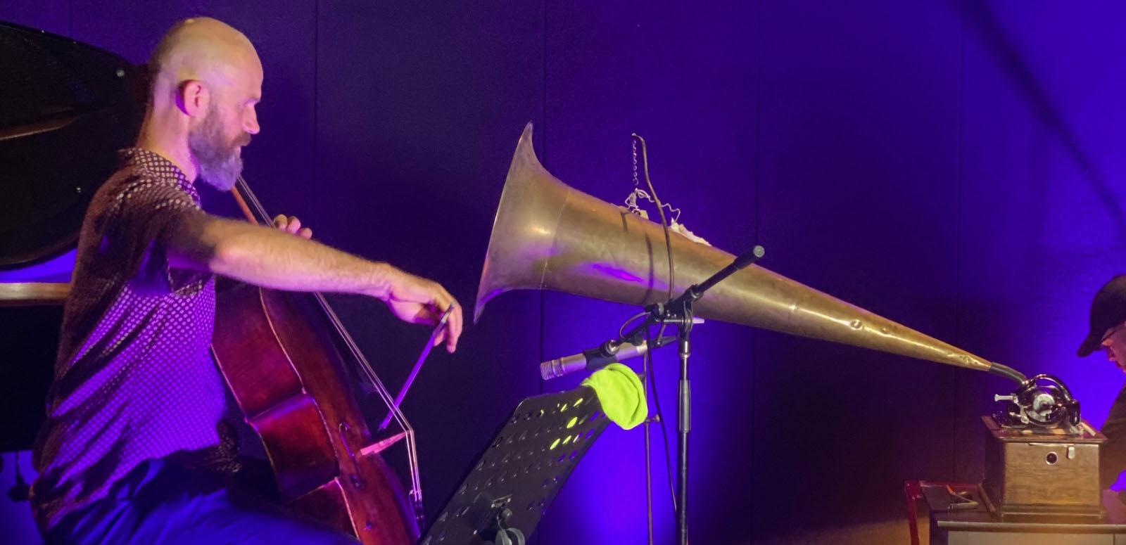Christopher Pidcock plays the cello into a large gramophone horm, to record a wax cylinder.