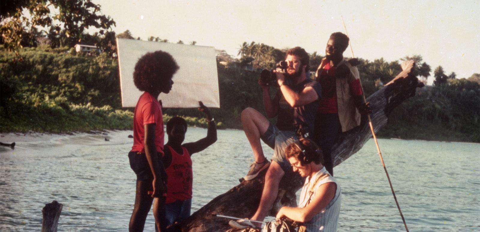 Filmmakers Chris Owen and Albert Toro balanced on a log overhanging the water and filming an actor in a scene from the film Tukana, shot off the coast of Papua New Guinea.