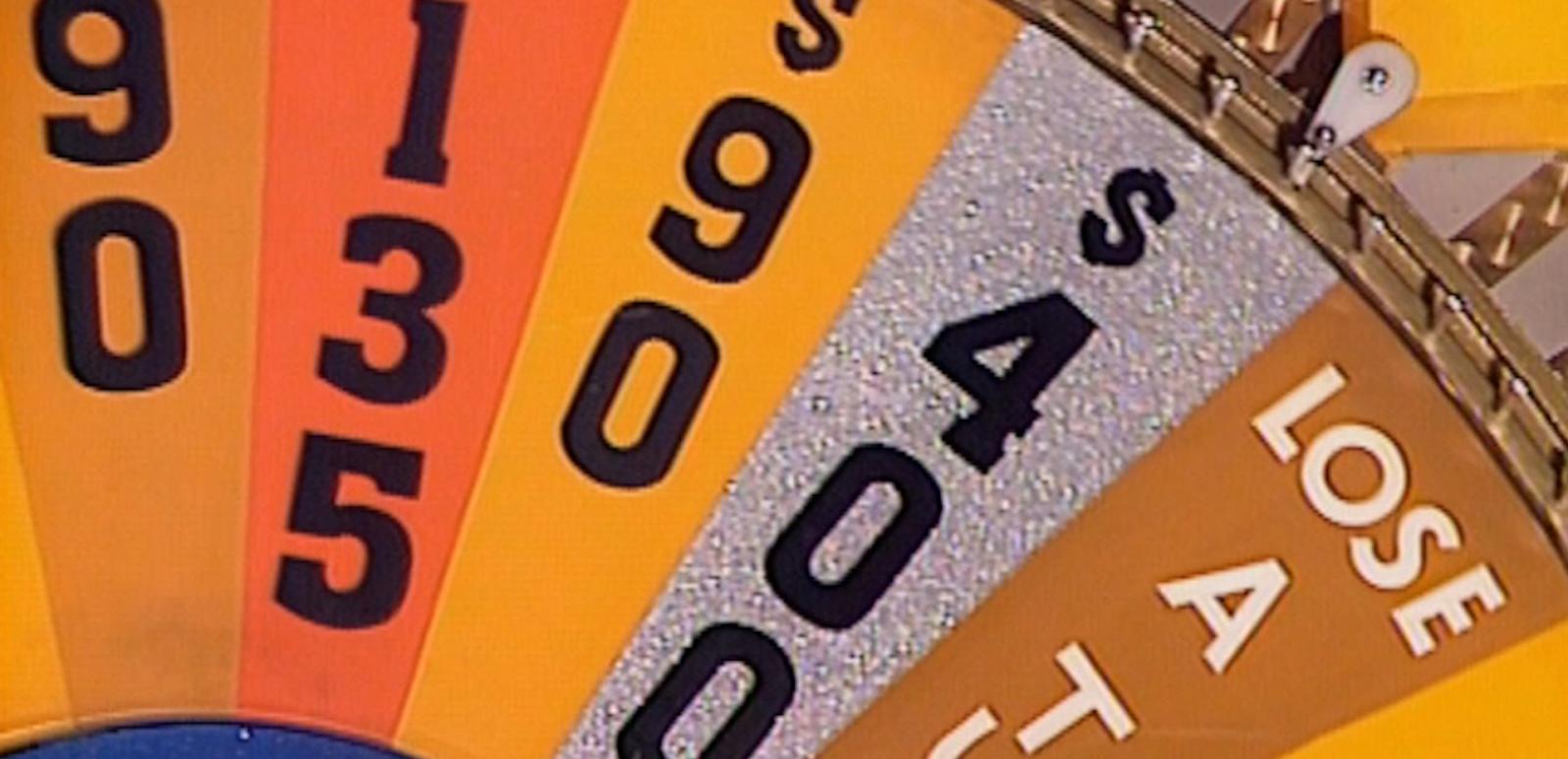 A close-up of the game wheel from TV show Wheel of Fortune showing segments with cash prizes and Lose a Turn.