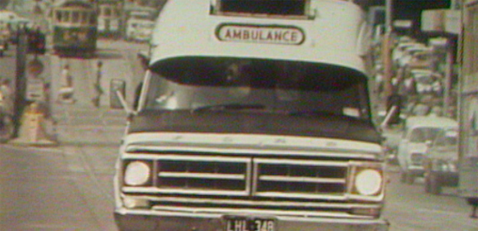 A 1970s ambulance driving to an accident scene.