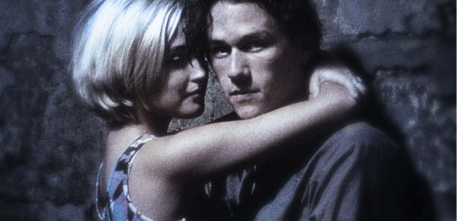 Heath Ledger as Jimmy and Rose Byrne as Alex in a still from Two Hands. The shot is grainy and plays with focus. They are in an embrace while they lean on a wall. Ledger looks at the camera.